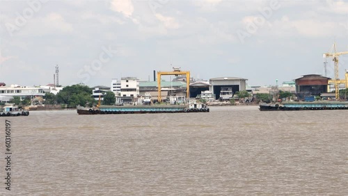 A group of boats tied in a row is pulled with cargo up the Chao Phraya River, Samut Prakan, Thailand, accelerated video photo