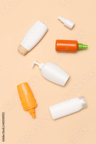 Different bottles of sunscreen cream on pale orange background