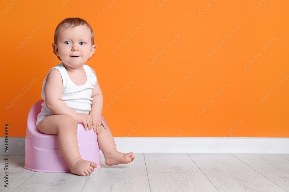 Little child sitting on baby potty near orange wall. Space for text Little child sitting on baby potty near orange wall. Space for text