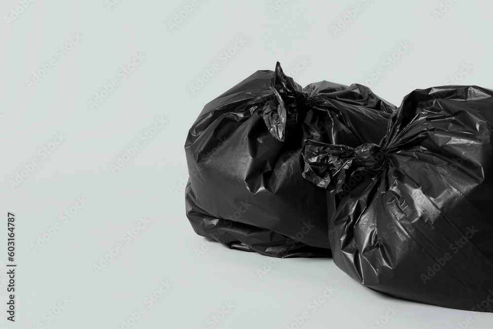 Trash bags full of garbage on light grey background. Space for text Trash bags full of garbage on light grey background. Space for text