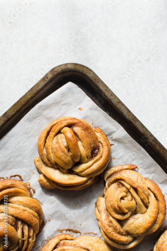 top view of Swedish cinnamon buns on a parchment lined baking sheet, cinnamon twists on a baking tray, top view of homemade Kanelbullar