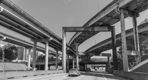 Driving on Texas highways with overpasses and underpasses, trees around, cars, and buildings on the left. 
