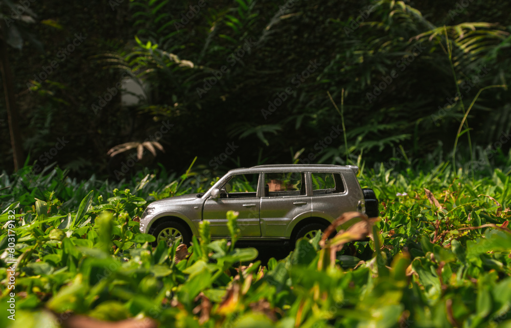 Concept for travelling with an SUV car. Photo of a toy car placed on the grass, after some edits.