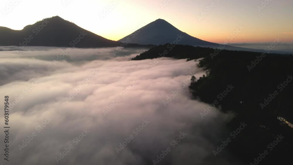 Drone scene of sunrise clouds touching the rainforest near Mount Batur in Bali, Indonesia. Flight through cloudscape with beautiful sky aerial shot. Perfect for cinema, background composition Drone scene of sunrise clouds touching the rainforest near Mount Batur in Bali, Indonesia. Flight through cloudscape with beautiful sky aerial shot. Perfect for cinema, background composition