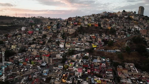 Aerial view away from a mountain full of slum homes, sunset favela Naucalpan, Mexico city - reverse, tilt, drone shot photo