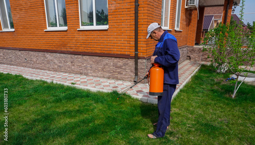 Obraz na płótnie A man works in the garden, spraying weeds from a sprayer. w salonie
