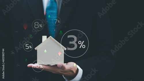 Real estate agent holding model house showing fluctuating interest rate concept ,Financial interest rates ,applying for financial credit ,interest burden ,The rise and fall of loan interest rates