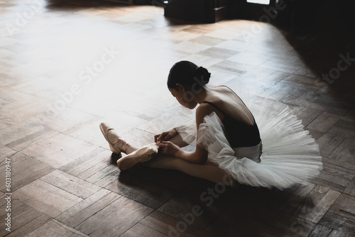teenage ballerina tying pointe shoes photo