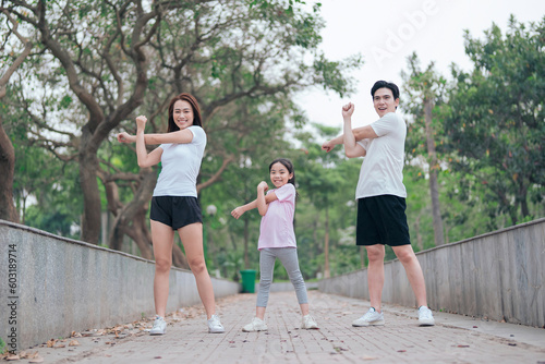 photo of young Asian family exercise at park