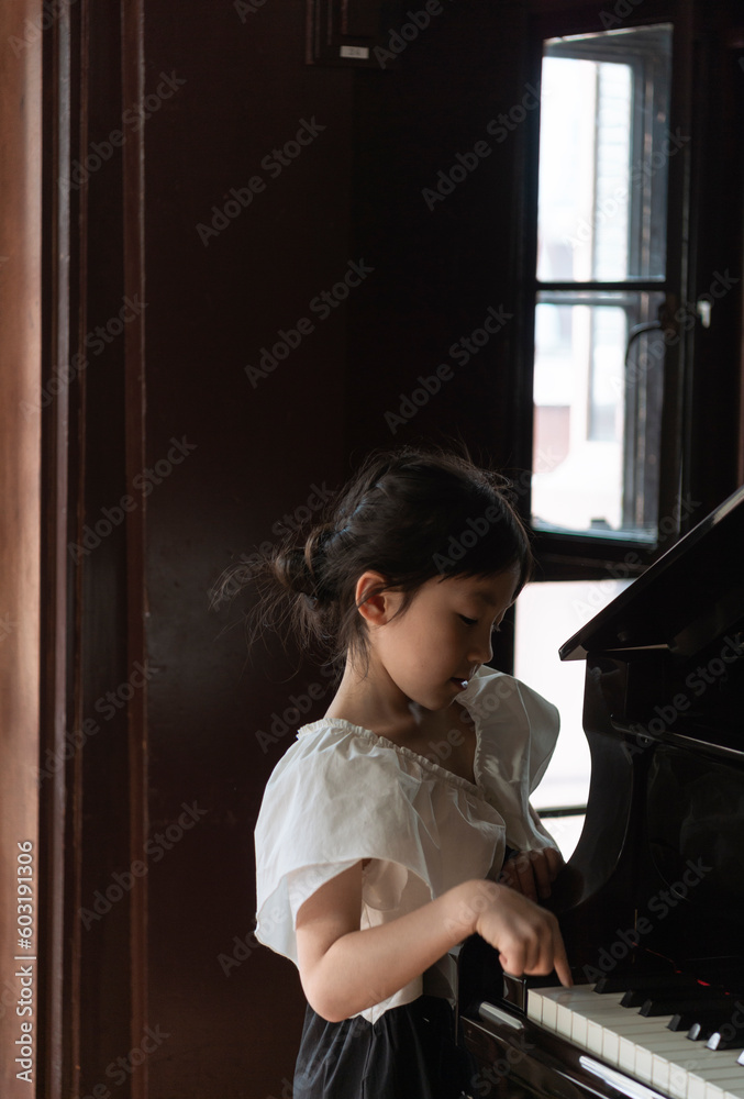 ピアノの側に立つアジア人の女の子のポートレート ピアノの側に立つアジア人の女の子のポートレート