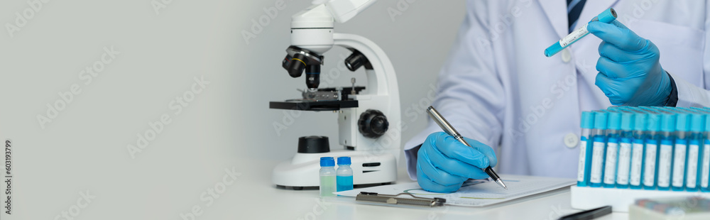 copy space, banner, panorama Scientists use scientific test tubes to record chemical data or drugs for testing and looking through a microscope in science laboratory for medicine biotechnology biology copy space, banner, panorama Scientists use scientific test tubes to record chemical data or drugs for testing and looking through a microscope in science laboratory for medicine biotechnology biology