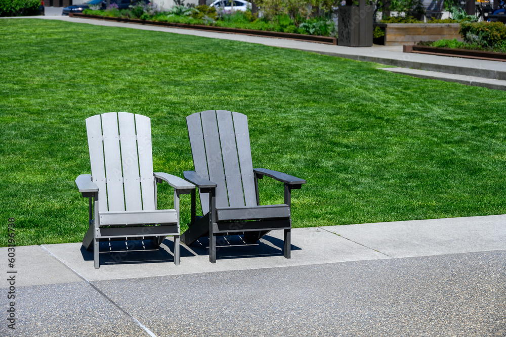 Two traditional gray Adirondack on a cement patio with vibrant green lawn in background
Two traditional gray Adirondack on a cement patio with vibrant green lawn in background