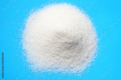 heap of sugar on blue background, white sugar for food and sweets dessert candy heap of sweet sugar crystalline granulated