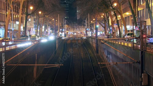 Timelapse with symmetrical arrangement of trams and traffic at the train station. Trams smoothly enter and exit while cars flow on the side. Tracks in the foreground provide a visual focal point. photo