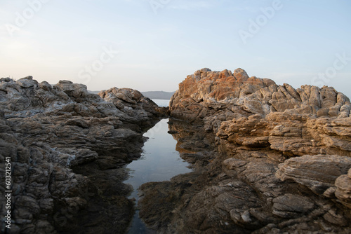 Two Sardinian rocks "kissing" each other and their mirror reflection in the still water of Porto Rotondo beach, Costa Smeralda, Italy