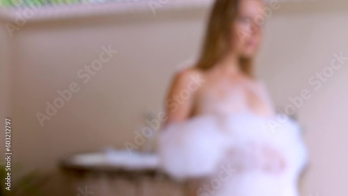 Blurred unfocused video of unrecognizable woman comes out of the bathroom covered in soapy foam after a spa in a resort or hotel. Concept of health, body care.