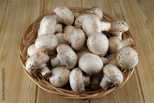 fresh champignons lie in a wicker plate on the table.
