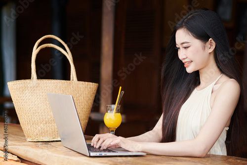 Smiling female solopreneur working on laptop at beach bar