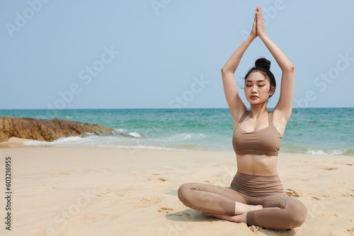 Fit young woman enjoying morning meditation on sea beach