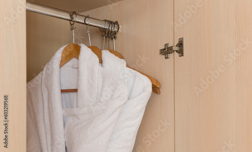 A white bathrobe hangs on a hanger. Close-up. Selective focus.