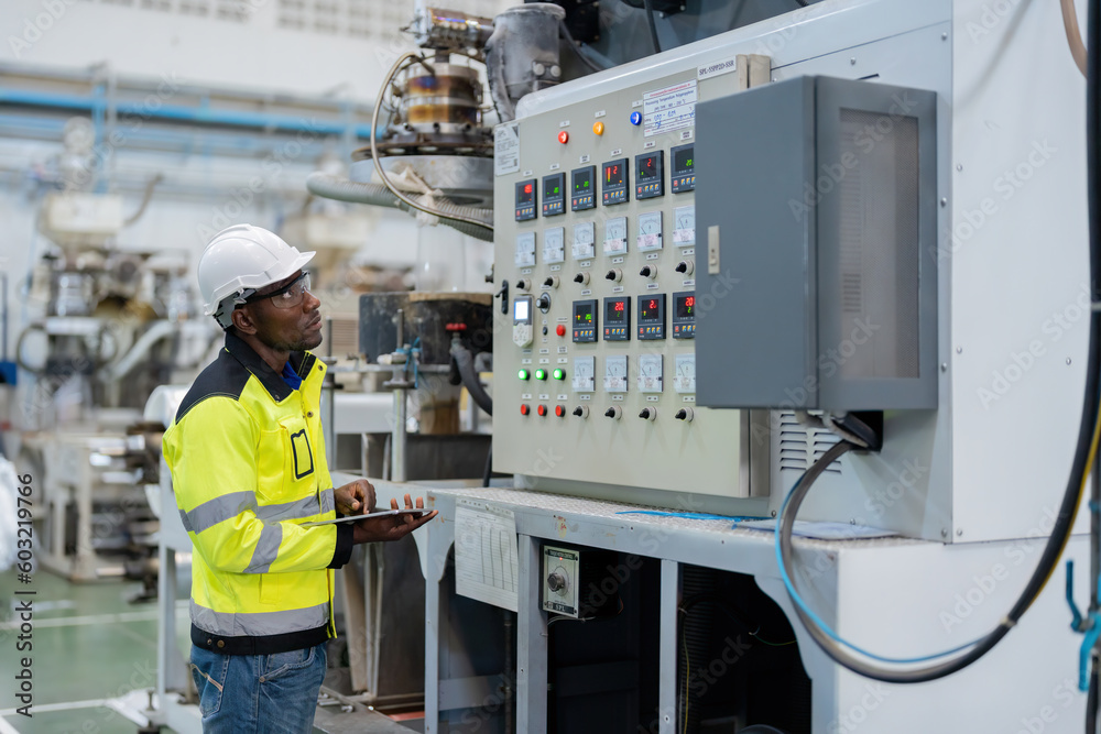 american engineer Stand to check the system through the tablet and see the production control circuit of the machine. in the plastic and steel industry Wear uniforms and helmets. american engineer Stand to check the system through the tablet and see the production control circuit of the machine. in the plastic and steel industry Wear uniforms and helmets.