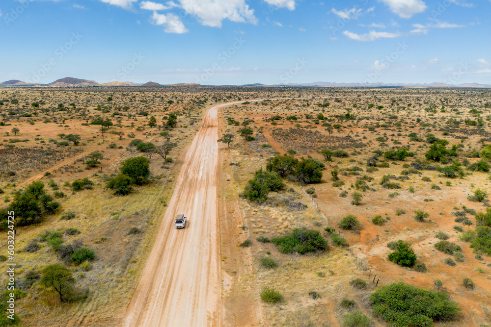 Drone image of offroad vehicle driving on dirt road in African bush