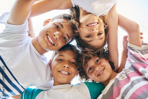 Portrait, low angle and a group of happy siblings or huddled together or hug in solidarity and smiling outdoors. Circle, brothers and sisters or excited children play or bonding and face outside photo