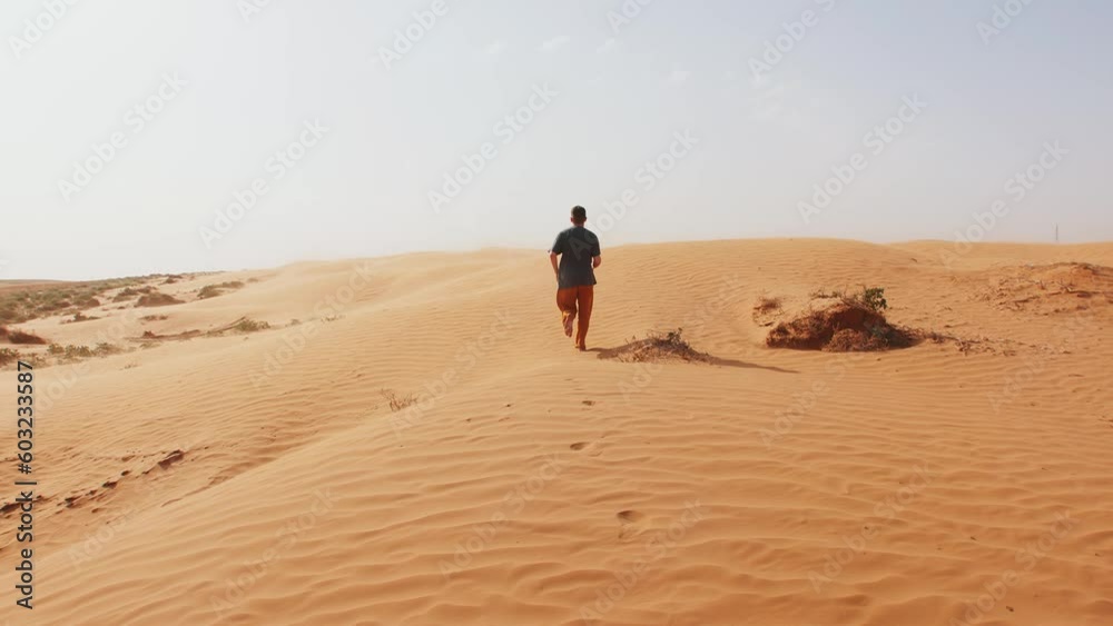 Young man runs barefoot on sandy hill in desert. Slow motion Young man runs barefoot on sandy hill in desert. Slow motion