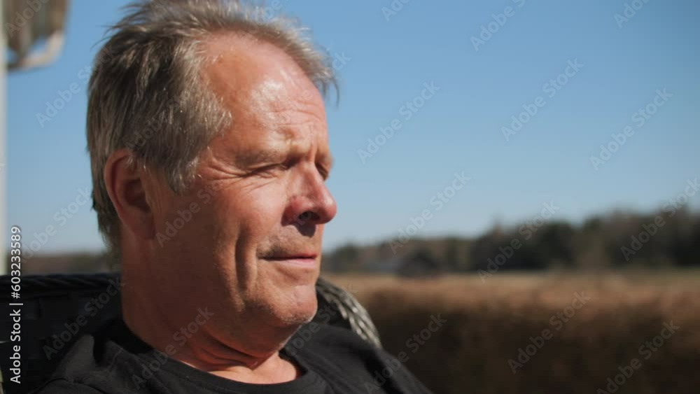 An older man shaking his head in disagreement while sitting outdoors