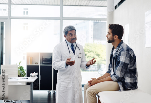 Healthcare, doctor and patient in consultation with expert advice, information and support in discussion. Medicine, health care and Indian man in doctors office consulting with medical professional.