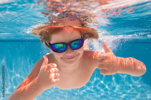 Child playing in swimming pool. Kids holidays and vacation concept. Summer kid play in swimming pool. Little child boy in pool underwater. Kids swim in pool on summer vacation.