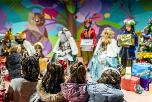 The three kings visiting children in a children's school, christian tradition, christmas festival in school, unrecognizable people, the background out of focus. photo