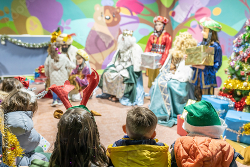 Fotografia The three kings visiting children in a children's school, christian tradition, christmas festival in school, unrecognizable people, the background out of focus