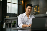 Handsome businessman working on his work on laptop at a modern loft coffee shop.