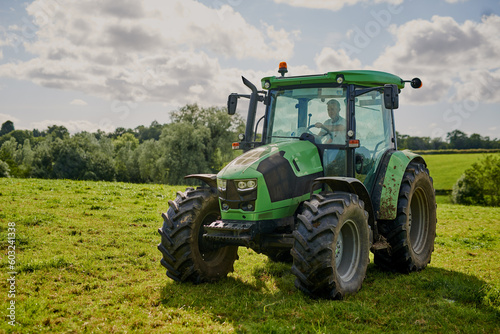Man  farm and green tractor on grass in countryside for agriculture  lawn or sustainability in nature. Male person or farmer in big agricultural machinery for farming  ecology or construction on land