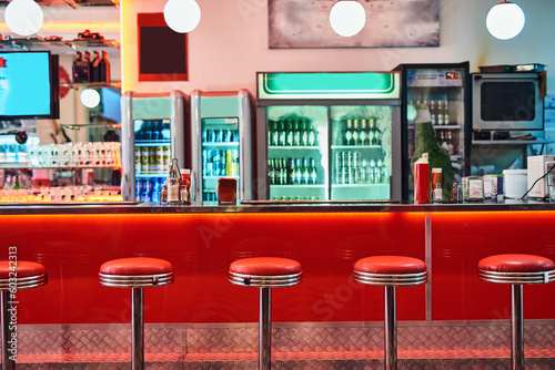Retro, vintage and stools with interior in a diner, restaurant or cafeteria with funky decor. Trendy, old school and chairs by a counter or bar in groovy, vibrant and stylish old fashioned empty cafe photo