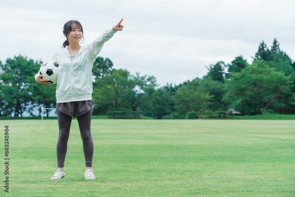 目標を指差すサッカーするファン・サポーターの日本人女性
