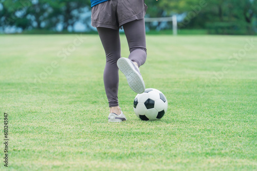 Fototapeta Naklejka Na Ścianę i Meble -  サッカーボールを蹴る・シュートする女性の足元
