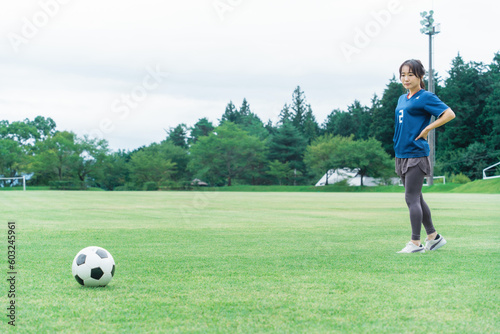 サッカー場でユニフォームを着てサッカー・フットサルの練習をする日本人女性
