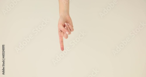 Woman hand shows downward direction using forefinger standing in premise. Index finger of hand indicates direction on light background slow motion