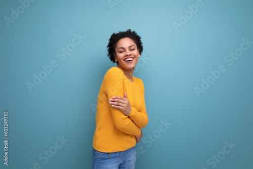 cute well-groomed young brunette latin female adult in a yellow sweater on a studio background with copy space