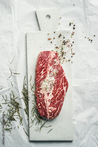 Fotomurale Raw marbled beef steak on white cutting board with herbs and salt