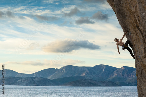 Young male climber hanging by a cliff