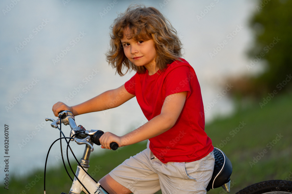 Obraz premium Child on bicycle. Boy in a helmet riding bike. Little cute caucasian boy in safety helmet riding bike in city park. Child first bike. Kid outdoors summer activities. Kid on bicycle. Boy ride a bike.