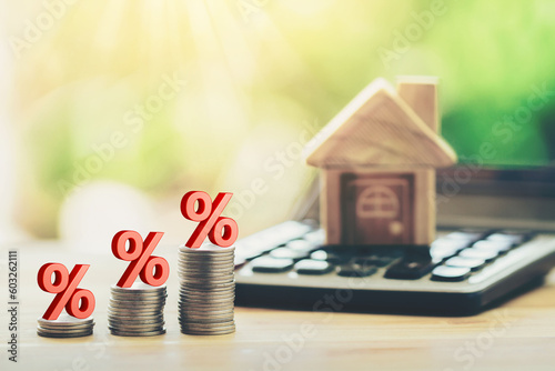Coins and house on the calculator And has an illustration of interest concept of calculating interest payments. planning savings money of coins to buy a home concept for property, mortgage, invest.