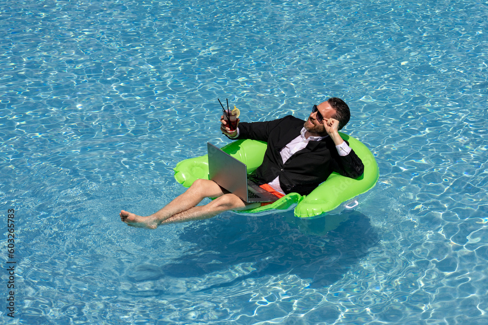 Crazy summer. Business drink summer cocktail and using laptop in suit in water pool. Fun business lifestyle. Funny businessman dreams about summer. Freelance concept, summer travel. Business success.