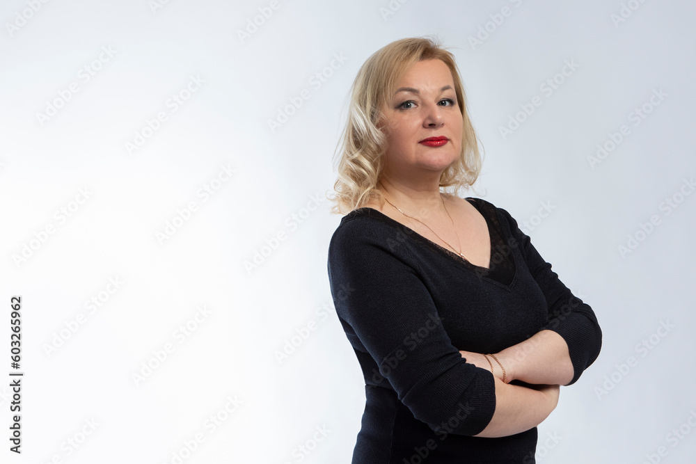 Alluring Winsome Mature Confident Caucasian Woman in Black Blazer With Hands Folded Over White Background. Alluring Winsome Mature Confident Caucasian Woman in Black Blazer With Hands Folded Over White Background.