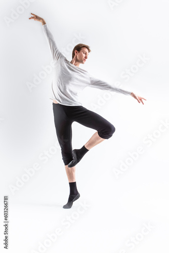 One Caucasian Handsome Young Man Dancing Ballet Posing in Dance Pose with Lifted hands in White Shirt On White.