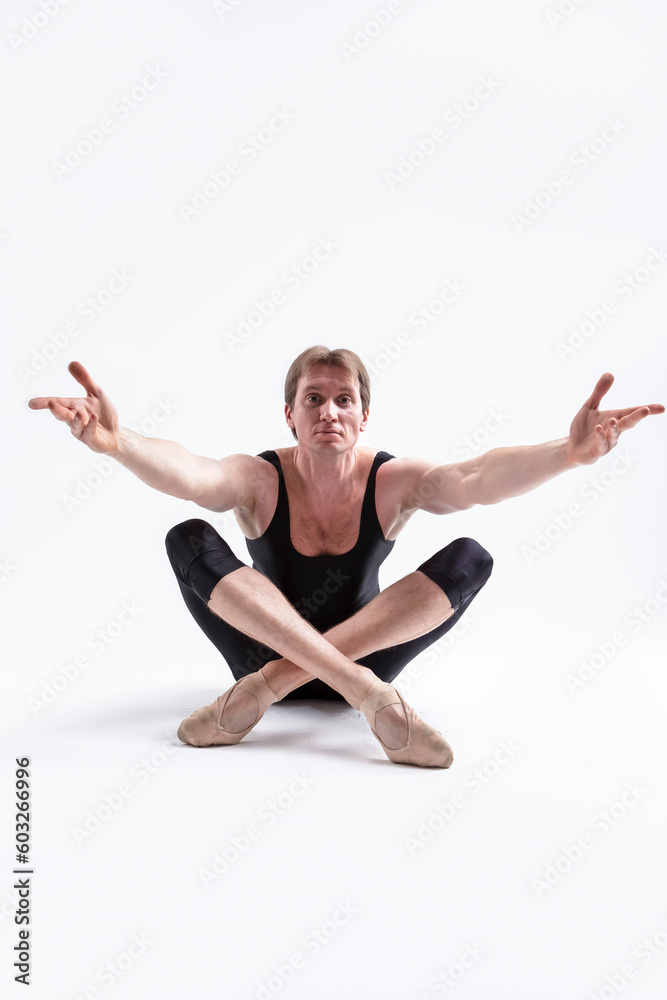 Ballerino Dancer Sitting While Practising Legs and Arms Forward Stretching Exercices Before Training In Black Sportive Tights in Studio. Ballerino Dancer Sitting While Practising Legs and Arms Forward Stretching Exercices Before Training In Black Sportive Tights in Studio.