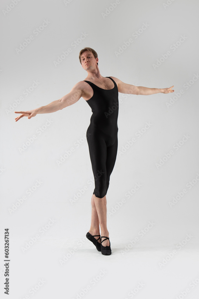Fototapeta premium Male Ballet Dancer Flexible Athletic Man Posing in Black Tights in Ballanced Dance Pose With Hands Horizontal